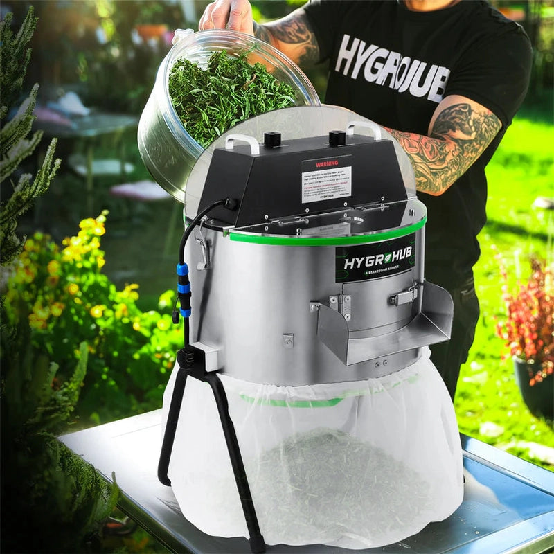 Person using a Hygrohub T250X Bud Trimmer with plants in an outdoor setting