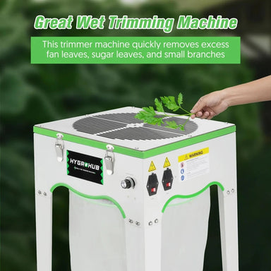 Hygrohub P100 Wet Bud Trimmer  with a hand placing green leaves on it against a blurred green background.