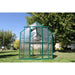 Grandio Element Greenhouse with transparent panels on a grassy area with trees in the background