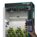 A Mars Hydro FC4000 320W 2x4 Smart Grow Tent Kit with iControl with reflective silver walls, black and teal trim, a top-mounted fan, grow light, and a digital control panel. A hand holds a smartphone showing the connected mobile app interface in front of the tent.